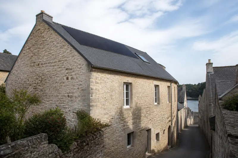 Panneaux solaires noirs posés au ras d'une toiture ancienne en tuiles